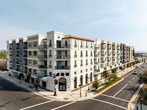 A street view of a row of apartment buildings with a clear blue sky above.