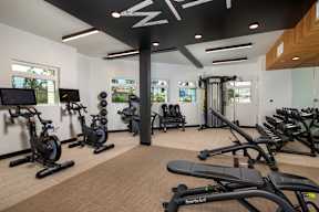 A gym with a variety of exercise equipment including treadmills, stationary bikes, and weight machines.
