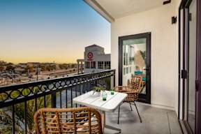 A balcony with a table and chairs overlooking a Target store.