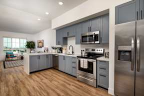 A modern kitchen with stainless steel appliances and wooden floors.