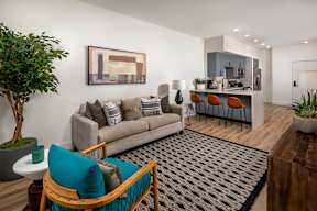 A living room with a grey couch, a blue chair, and a painting on the wall.