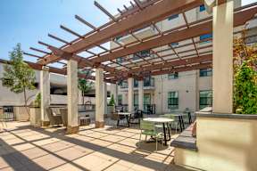 A patio with tables and chairs under a wooden pergola.