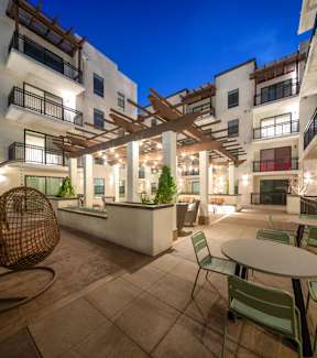 A patio with a table and chairs is surrounded by apartment buildings.