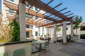 A patio with a table and chairs under a wooden pergola.