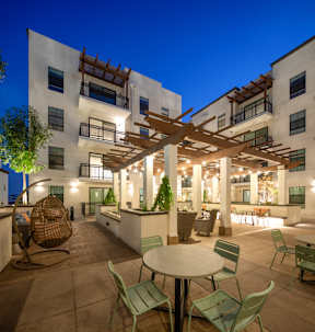 A patio with a table and chairs is illuminated by lights.