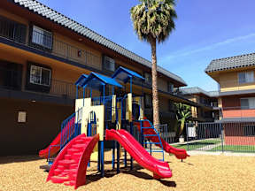 A playground with a red slide and a blue canopy.