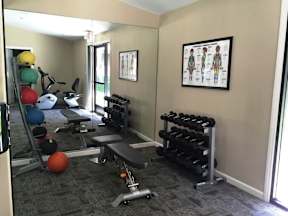 A gym room with a bench, weights, and exercise balls.