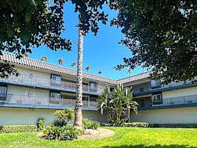 Cozy exterior of Oro Apartments from the interior courtyard with lush greenery, poolside views and more!