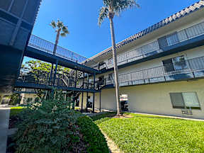 Cozy exterior of Oro Apartments from the interior courtyard with lush greenery, poolside views and more!