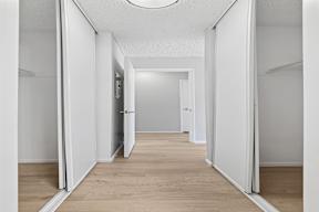 Hallway in Oro apartment home leading to bedroom with wood-style plank flooring and closets lining the halls for optimal storage