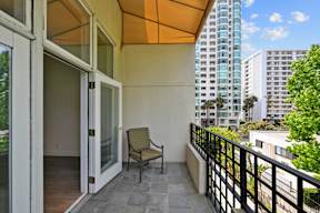 A balcony with a chair and a table with a glass door.