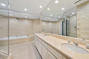 A bathroom with a large mirror, a sink, and a bathtub.