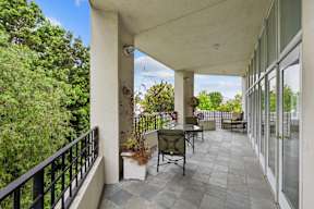 A patio with a table and chairs overlooks a lush green yard.