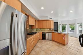 A modern kitchen with wooden cabinets and a stainless steel refrigerator.