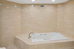 a large white bath tub in a bathroom with beige tiles