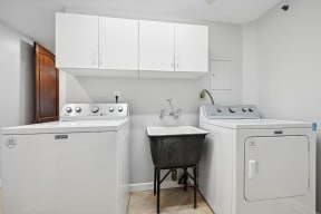 a white laundry room with two washes and a sink