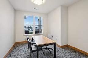 A conference room with a long table and chairs located at Deforest Yards apartments in DeForest, WI