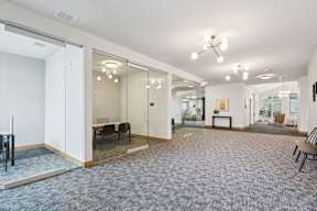 A spacious room with a grey carpet and a glass wall.