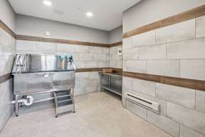 A kitchen with a stainless steel refrigerator and a wall of tiles.