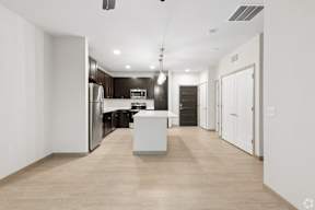 A modern kitchen with a white island in the middle with quartz countertops  located at Deforest Yards apartments in DeForest, WI