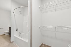 A white bathroom with a walk in shower and a towel rack located at Deforest Yards apartments in DeForest, WI