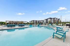 A large outdoor swimming pool with lounge chairs and a building in the background.