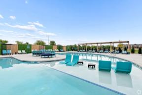 A large outdoor swimming pool with lounge chairs and a shaded area.