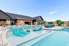 A large outdoor swimming pool with lounge chairs and a building in the background.