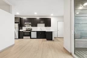 A modern kitchen with black cabinets and stainless steel appliances located at Deforest Yards apartments in DeForest, WI