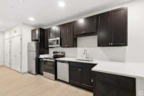 A kitchen with black cabinets and white countertops located at Deforest Yards apartments in DeForest, WI