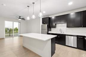 A modern kitchen with black cabinets and a white island located at Deforest Yards apartments in DeForest, WI