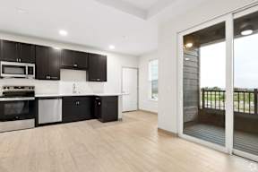 A modern kitchen with black cabinets and stainless steel appliances located at Deforest Yards apartments in DeForest, WI