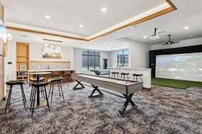 A game room with a pool table and chairs, a bar area, and a golf simulator located at Deforest Yards apartments in DeForest, WI