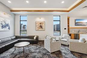 A modern longue with a black leather sofa and a wooden coffee table and coffee bar located at Deforest Yards apartments in DeForest, WI