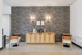 A coffee bar with a wooden cabinet and chairs located at Deforest Yards apartments in DeForest, WI