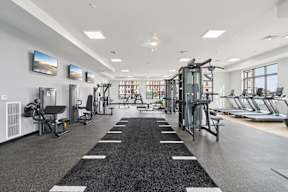 A spacious gym with a variety of equipment and a large mirror on the wall located at Deforest Yards in DeForest, WI