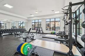 A fitness center with a variety of equipment including a weight rack and a barbell located at Deforest Yards apartments in DeForest, WI