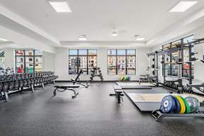 A spacious fitness center with a variety of equipment including weights and weight plates located at Deforest Yards apartments in DeForest, WI