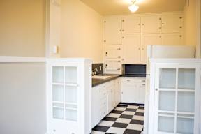 A kitchen with white cabinets and a black and white checkered floor.