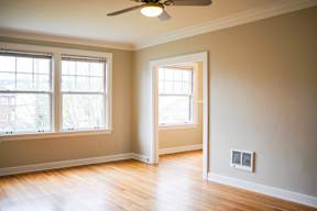 A room with a ceiling fan and two windows.