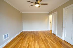 A room with a ceiling fan and wooden floors.