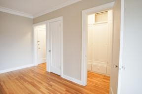 A room with two white doors and wooden floors.