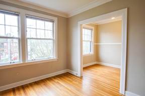 A room with wooden floors and two windows.