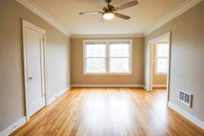 A room with a ceiling fan and wooden floors.