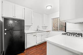 Kitchen with white cabinets, gas range and a black refridgerator
