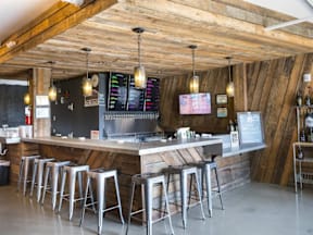 A bar with a wooden ceiling and stools.