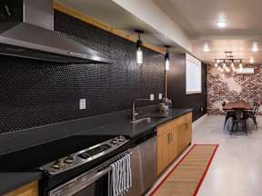 A modern kitchen with a stove top oven and a black counter top.
