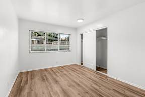 A room with a window and a wooden floor.