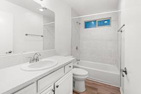 A white bathroom with a toilet, sink, and bathtub.