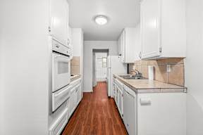 A kitchen with white appliances and cabinets.